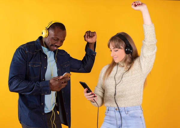Pareja Bailando Escuchar Música Sus Teléfonos Móviles Fondo Amarillo —  Fotos de Stock