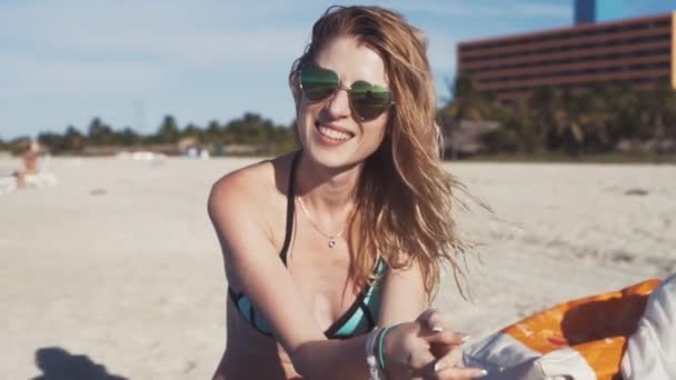 Дівчина в сонцезахисних окулярах на пляжі, посміхаючись — стокове відео
