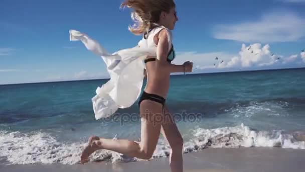 Menina com cabelo fluttering corre ao longo da praia — Vídeo de Stock