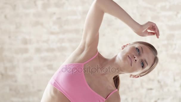 The Yogi girl is doing exercises in the middle of a large bright room. — Stock Video