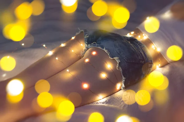 Beautiful young woman smiling and talking garlands of lights in home — 스톡 사진
