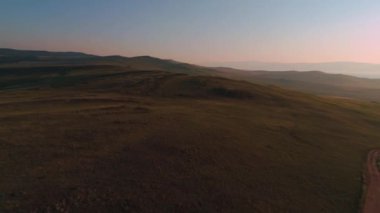 Kuru sarı otlardan oluşan hava sahası. Olkhon Adası 'ndaki Steppe. Baykal Gölü, Rusya. İnsansız hava aracı günbatımındaki tepeler