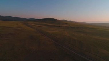 Kuru sarı otlardan oluşan hava sahası. Olkhon Adası 'ndaki Steppe. Baykal Gölü, Rusya. İnsansız hava aracı günbatımındaki tepeler