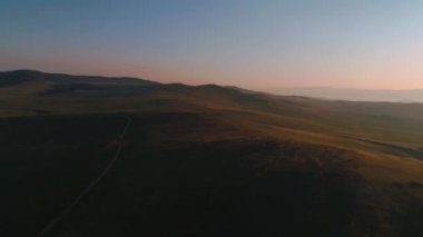 Kuru sarı otlardan oluşan hava sahası. Olkhon Adası 'ndaki Steppe. Baykal Gölü, Rusya. İnsansız hava aracı günbatımındaki tepeler