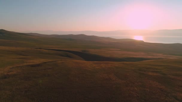 Campo aéreo de grama amarela seca. Estepe em Olkhon Island. Lago Baikal, Rússia. Colinas de imagens de drones ao pôr-do-sol — Vídeo de Stock