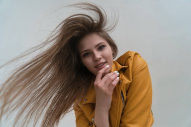 Stüdyoda poz veren uzun saçlı, açık tenli genç bir kız. Geniş açı mercek ve kameraya bak..