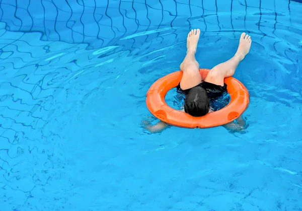Маленький мальчик плавает с оранжевым кольцом в бассейне — стоковое фото