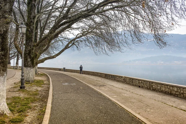 Brouillard sur le lac et femme seule sur une route pour piétons — Photo