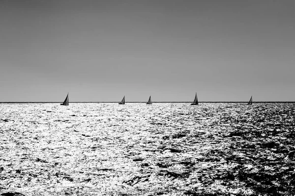 小さな太陽が低い現状銀の海でボートのレースをセーリングします 白黒銀の効果適用 秩序正しいシンメトリー構図 — ストック写真