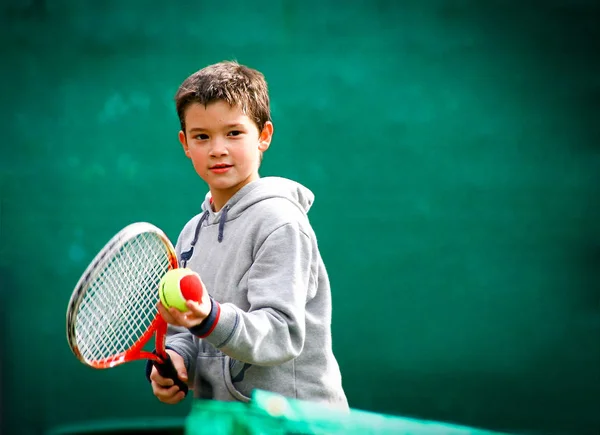 Piccolo tennista su sfondo verde sfocato . Immagine Stock