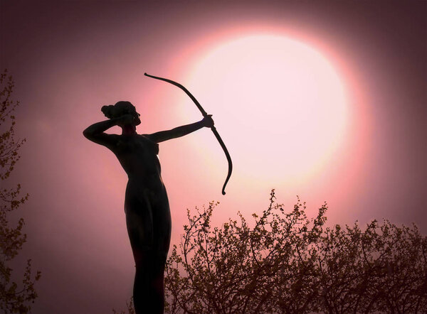 Statue of a woman Archer Silhouette with a bow target the sun
