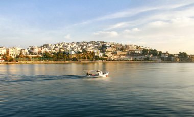 Küçük ahşap bir teknesi olan balıkçı gün doğumunda balık tutmaya gider. Kastela, marina Zeas, Pire, Yunanistan.