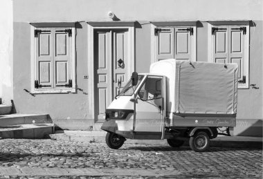 Üç tekerli mini beyaz kamyon, teslimat için ideal ve fotoğrafta gösterildiği gibi küçük caddelerde küçük işletmeler. Syros Adası, Cyclades, Yunanistan