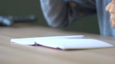 Açık ahşap bir masanın üzerinde bir yay üzerinde açık bir defter yatıyor. Görüntüyü kapat.