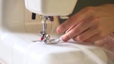 Sewing process. The seamstress files transparent curtains on a sewing machine. Close up view.