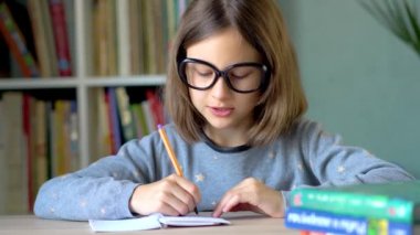 The child writes a solution to the problem in a notebook. An emotional look in front of you. Close up view.