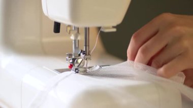 Beyaz ağ kumaşı. Terzi dikiş makinesine şeffaf perdeler diker. Görüntüyü kapat.