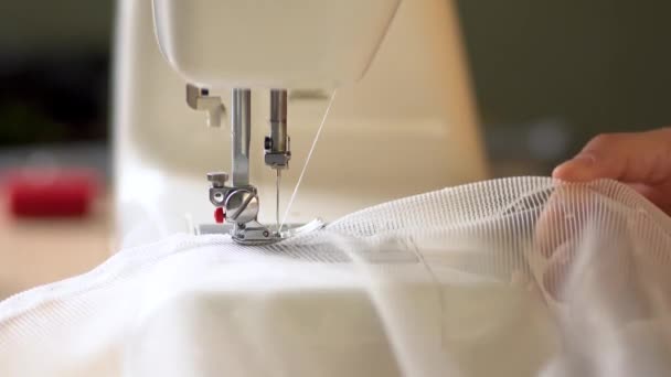 Proces obszywania krawędzi zasłon z białej tkaniny siatkowej na maszynie do szycia. Widok z bliska. — Wideo stockowe