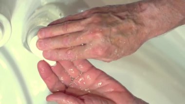 Vücudu mikroplardan ve virüslerden koruma kavramı. Sabun ve köpük uygulayan yaşlı adamın eli