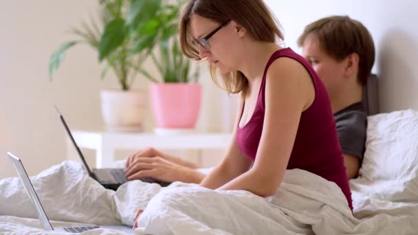 Een man en vrouw werken in de slaapkamer op een laptop. — Stockvideo