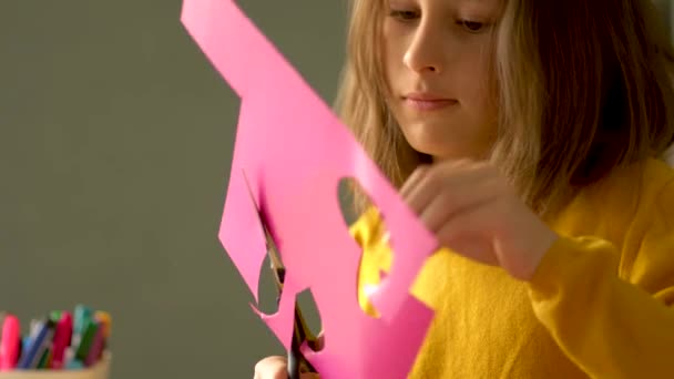 Fernunterricht von Kindern zu Hause während der Coronavirus-Quarantäne Covid 19. Eine Schülerin erfüllt eine kreative Aufgabe aus Papier. — Stockvideo