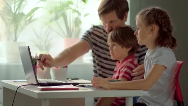 Aprendizaje a distancia para niños en casa. Padre explica material escolar a la hija y el hijo con una computadora portátil . — Vídeos de Stock