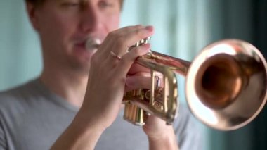 Genç bir adam trompet çalıyor. Eller yakın görünüm