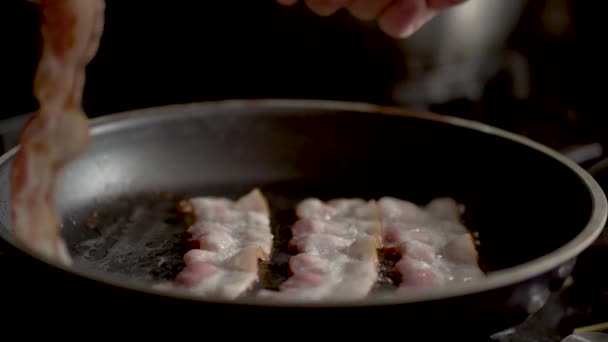 El cocinero voltea el tocino frito en una sartén. Vista de cerca — Vídeo de stock