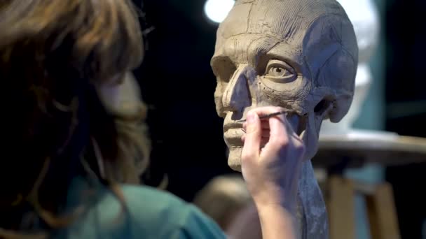 Femme sculptrice à l'œuvre sur une sculpture d'une tête humaine. — Video