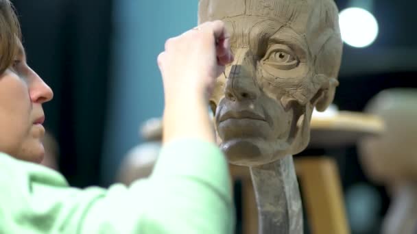 Femme sculptrice à l'œuvre sur une sculpture d'une tête humaine. — Video