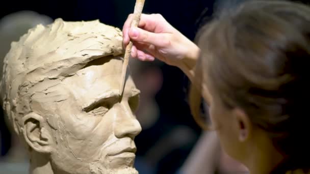 Vrouw beeldhouwer aan het werk op een sculptuur van een menselijk hoofd. — Stockvideo