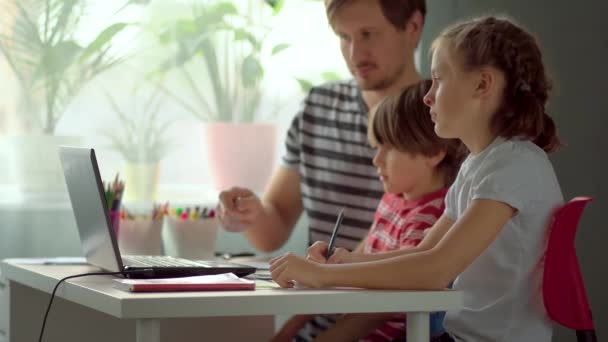 Pai explica filho e filha lição de casa usando um laptop tablet digital . — Vídeo de Stock