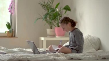 Tatlı çocuk eğitim için dizüstü bilgisayar kullanıyor, online öğrenim görüyor, evde eğitim görüyor. Kızın evde ödevi var..