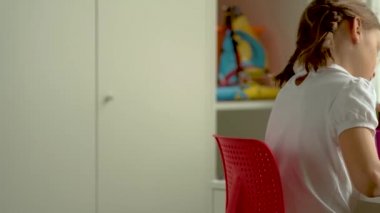 Tatlı çocuk eğitim için dizüstü bilgisayar kullanıyor, online öğrenim görüyor, evde eğitim görüyor. Kızın evde ödevi var..
