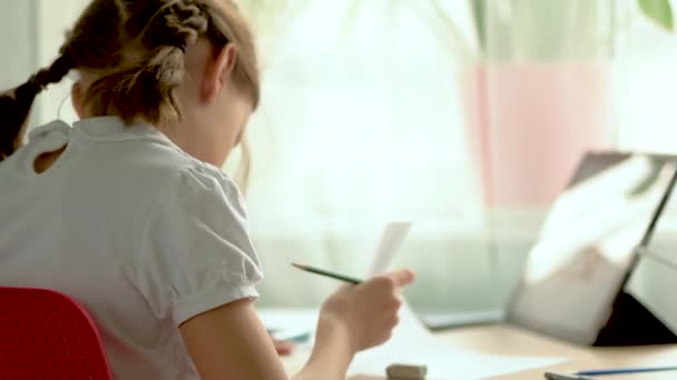 O portátil bonito do uso da criança para a instrução, estudo em linha, casa que estuda. Menina tem dever de casa na escola em casa. — Vídeo de Stock