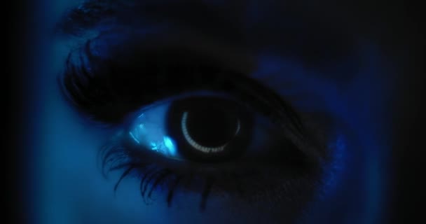 Detailní záběr ženského oka s krásnou party make-up, dlouhé černé řasy, otevření v tmavě modrém osvětlení. Zpomal, temné studiové světlo. Skrytá 4k