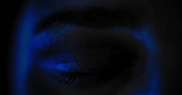 Detailní záběr ženského oka s krásným make-upem, otevírající se v tmavomodrém světle. Zpomal, temné studiové světlo. Skrytá 4k