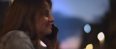 Telefonda konuşan ve arka planda Bokeh ışıkları olan bir kafede kahkahalar atan genç bir kadını yakından çek. Sığ dof, gerçek zamanlı, Bmpcc 4k