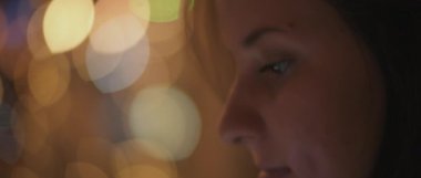 Telefonuna bakan genç bir kadının yüzünü kapatın. Arka planda gece lambaları var. Sığ dof, gerçek zamanlı, Bmpcc 4k