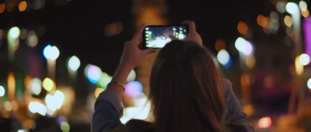 Молодая Женщина Фотографирует Ночной Город Посреди Улицы Улыбается Боке Огни — стоковое видео