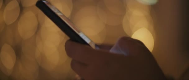 紧紧抓住一个年轻女人的手 输入一条信息 用她的电话发短信 背景上挂着防波针灯 浅色Dof Bmpcc — 图库视频影像