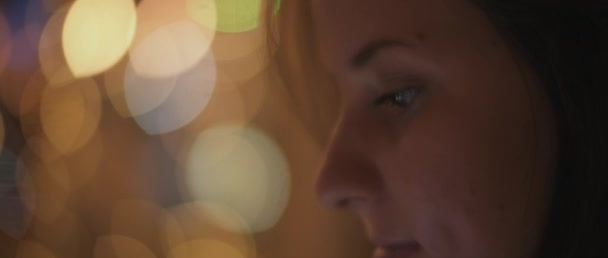 若い女性の顔の彼女の携帯電話を見て閉じると 背景に夜の街のボケライト 浅いDof リアルタイム Bmpcc — ストック動画