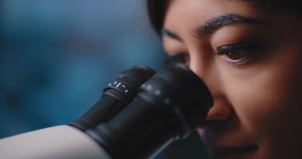 Закріплення Жіночих Наукових Очей Дивлячись Зразки Під Мікроскопом Синє Світло — стокове відео