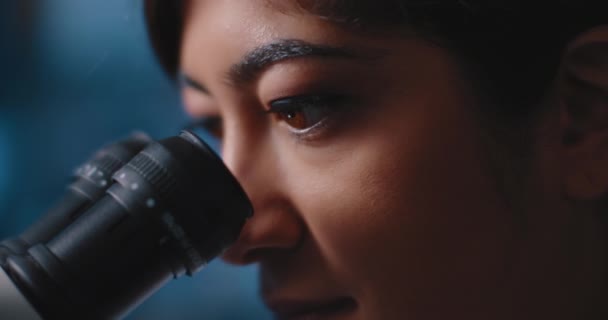 Закріплення Жіночих Наукових Очей Дивлячись Зразки Під Мікроскопом Синє Світло — стокове відео