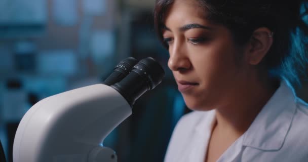 Cientista Pesquisa Feminina Olhando Para Amostras Sob Microscópio Iluminação Azul — Vídeo de Stock