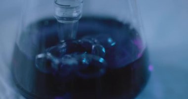 Laboratuvardaki kimyasallarla yapılan bir deney sırasında konik bir şişenin içindeki pipetten çıkan baloncuklar. Yakın çekim, el kamerası, yavaş çekim, Bmpcc 4k ile. Kavram: Bilim, kimya