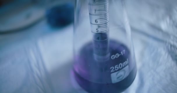 研究室で反応のための化学物質をテストするために円錐フラスコから紫色の液体を取り出す科学者 閉じる スローモーション トラッキングショット ハンドヘルド Bmpcc 4Kで撮影 — ストック動画