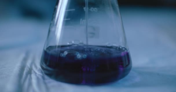 Scientifique ajoutant un liquide pourpre à une fiole conique pour tester les substances chimiques pour les réactions dans un laboratoire. Gros plan, main, ralenti, prise de vue avec BMPCC 4K. Concept : science, chimie 