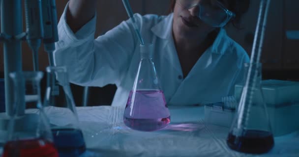 Female Research Scientist Adding Liquid Conical Flask Blue Lighting Dark — 비디오