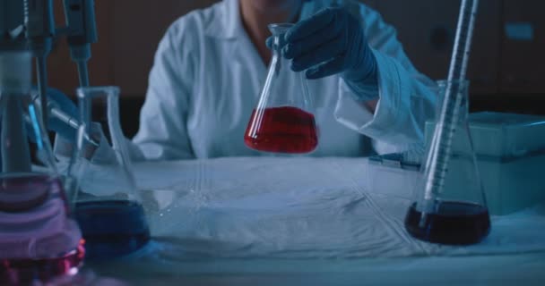 Chercheuse Mélangeant Une Fiole Conique Avec Liquide Rouge Eclairage Bleu — Video